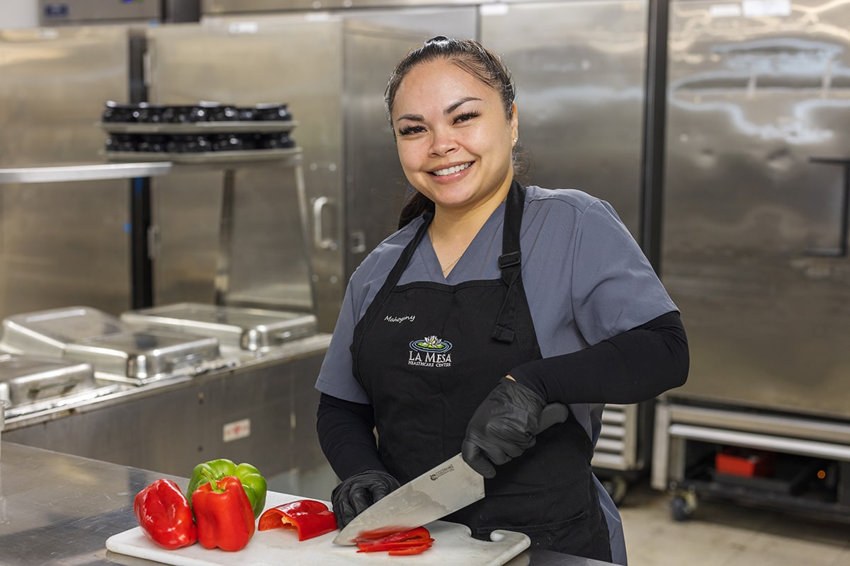 a kitchen staff member cutting vegetables at La Mesa facility