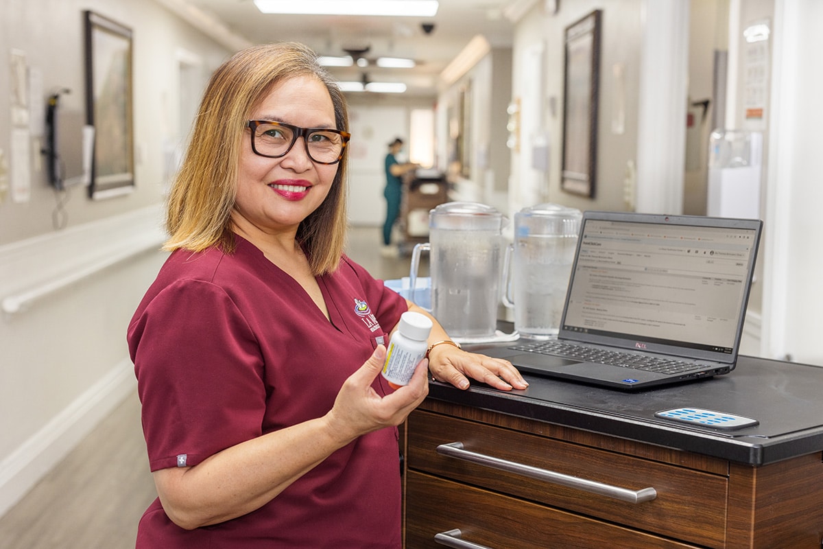 A nurse at a nurse's cart in the hallway at La Mesa facility